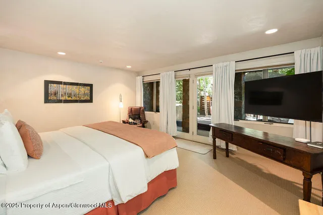 a spacious bedroom with a bed and a flat screen tv