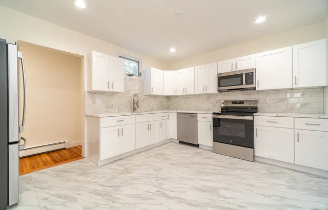 a kitchen with granite countertop white cabinets and stainless steel appliances