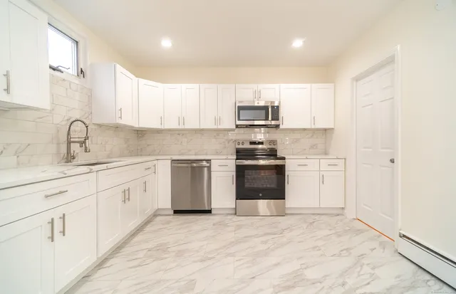 a kitchen with kitchen island white cabinets appliances and sink