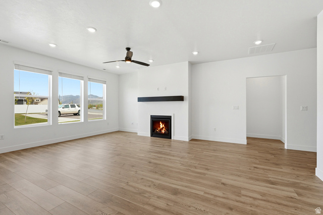 401 West 3085 South, Unit 329 Nibley, UT 84321 - Photo 13 of 34 Unfurnished living room featuring ceiling fan, a lit fireplace, light wood-style floors, recessed lighting, and a mountain view
