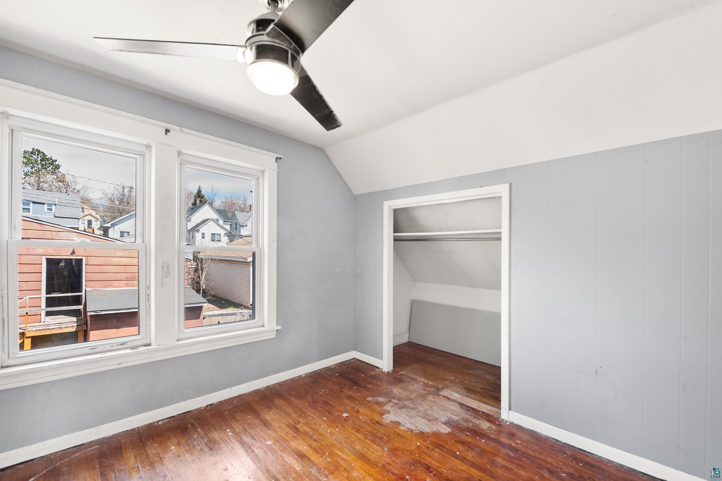3067 Restormel Street Duluth, MN 55806 - Photo 14 of 25 Room featuring wood-finish flooring, two large windows with white trim, and a built-in closet with a hanging rod