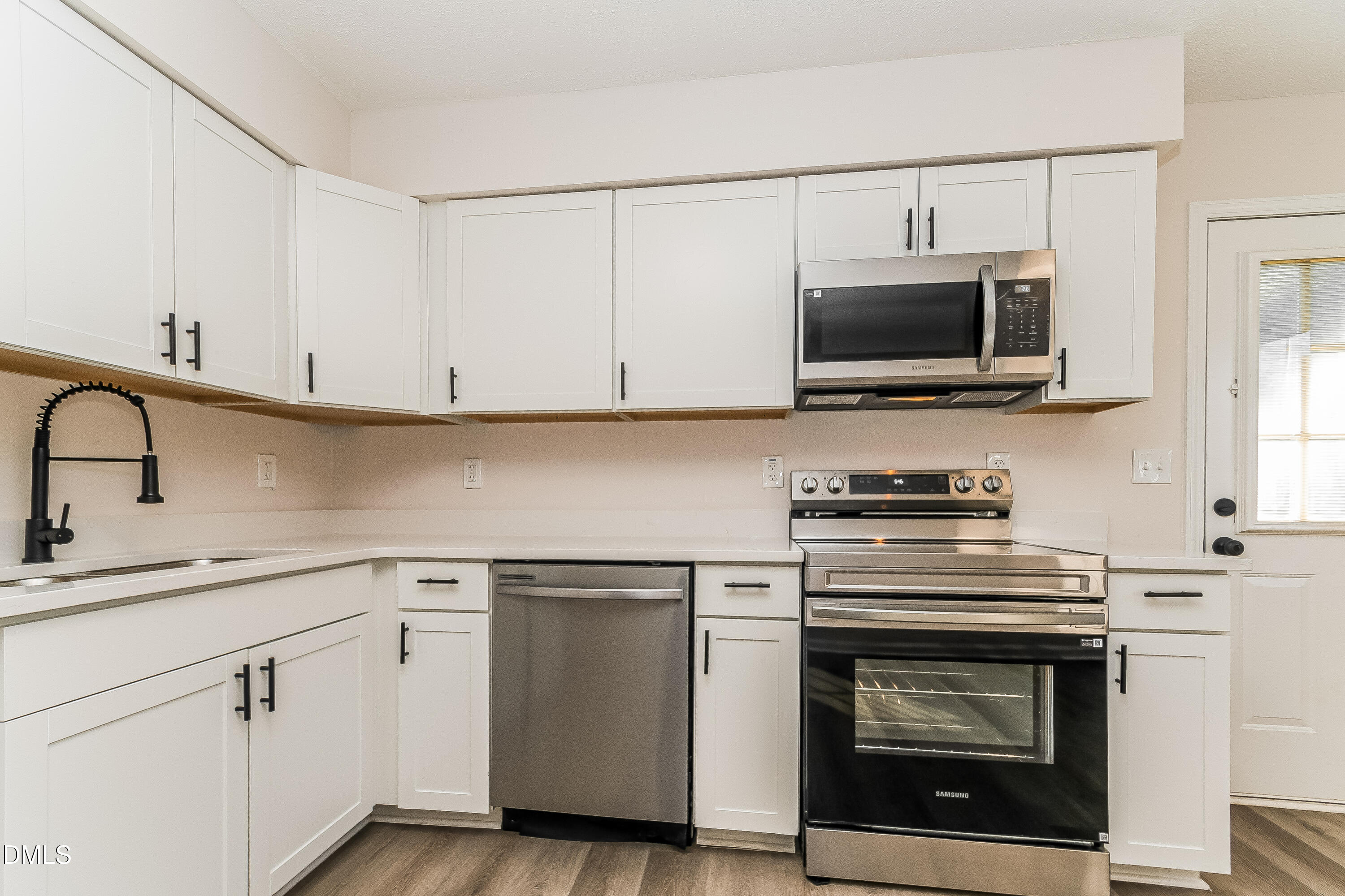 418 Craven Street Durham, NC 27704 - Photo 3 of 14 a kitchen with white cabinets stainless steel appliances and sink