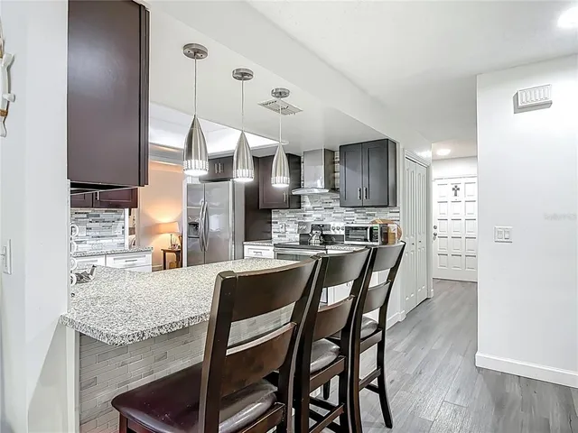 a kitchen with granite countertop a table chairs microwave and cabinets