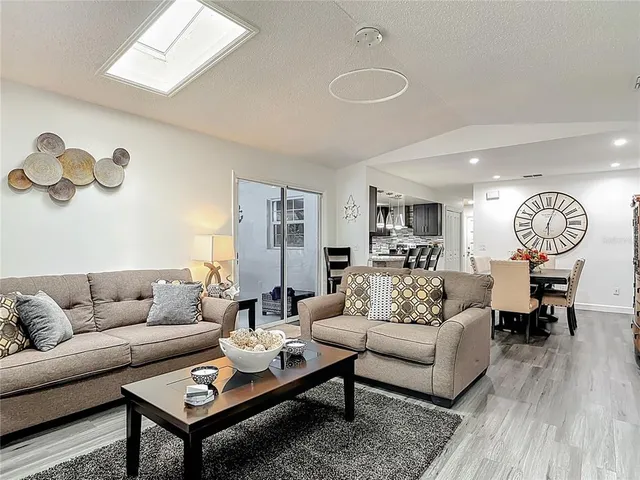 a living room with furniture a rug potted plant and a window