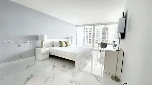 a bedroom with a bed and a flat tv screen on the dresser