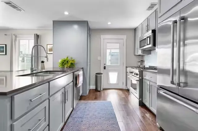 a large kitchen with stainless steel appliances a sink and cabinets