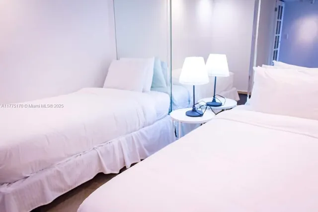 a bedroom with two bed and a lamp