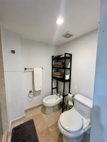 a white toilet sitting next to a bathroom sink and a mirror