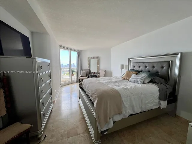 a living room with furniture a flat screen tv and a refrigerator