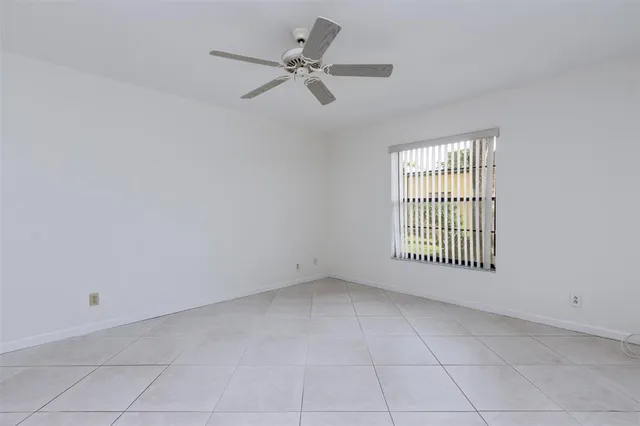 an empty room with a ceiling fan and a window