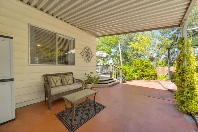 a backyard of a house with table and chairs with potted plants
