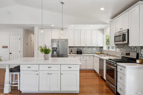 a kitchen with white cabinets stainless steel appliances and wooden floor