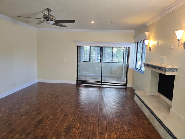 an empty room with wooden floor fireplace and windows