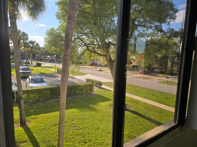 a view of a livingroom with wooden floor a ceiling fan and windows