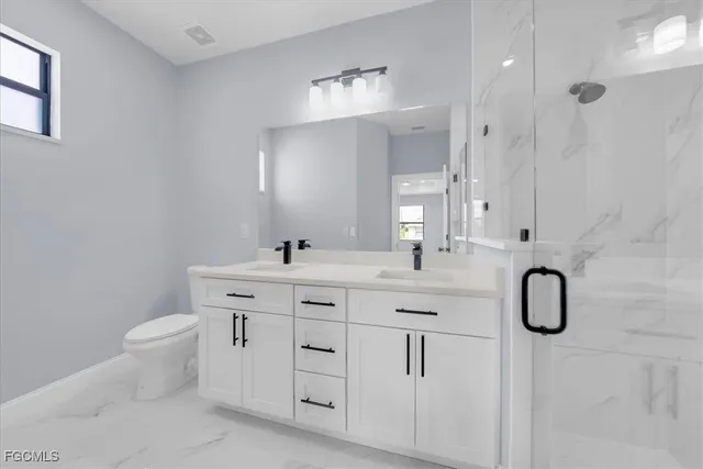 a bathroom with a double vanity sink mirror and toilet