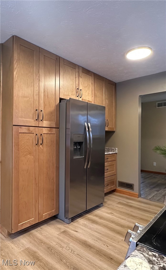 4811 West Pleasant Valley Road Cleveland, OH 44129 - Photo 9 of 31 Kitchen featuring stainless steel appliances, light wood-style floors, brown cabinetry, and a textured ceiling