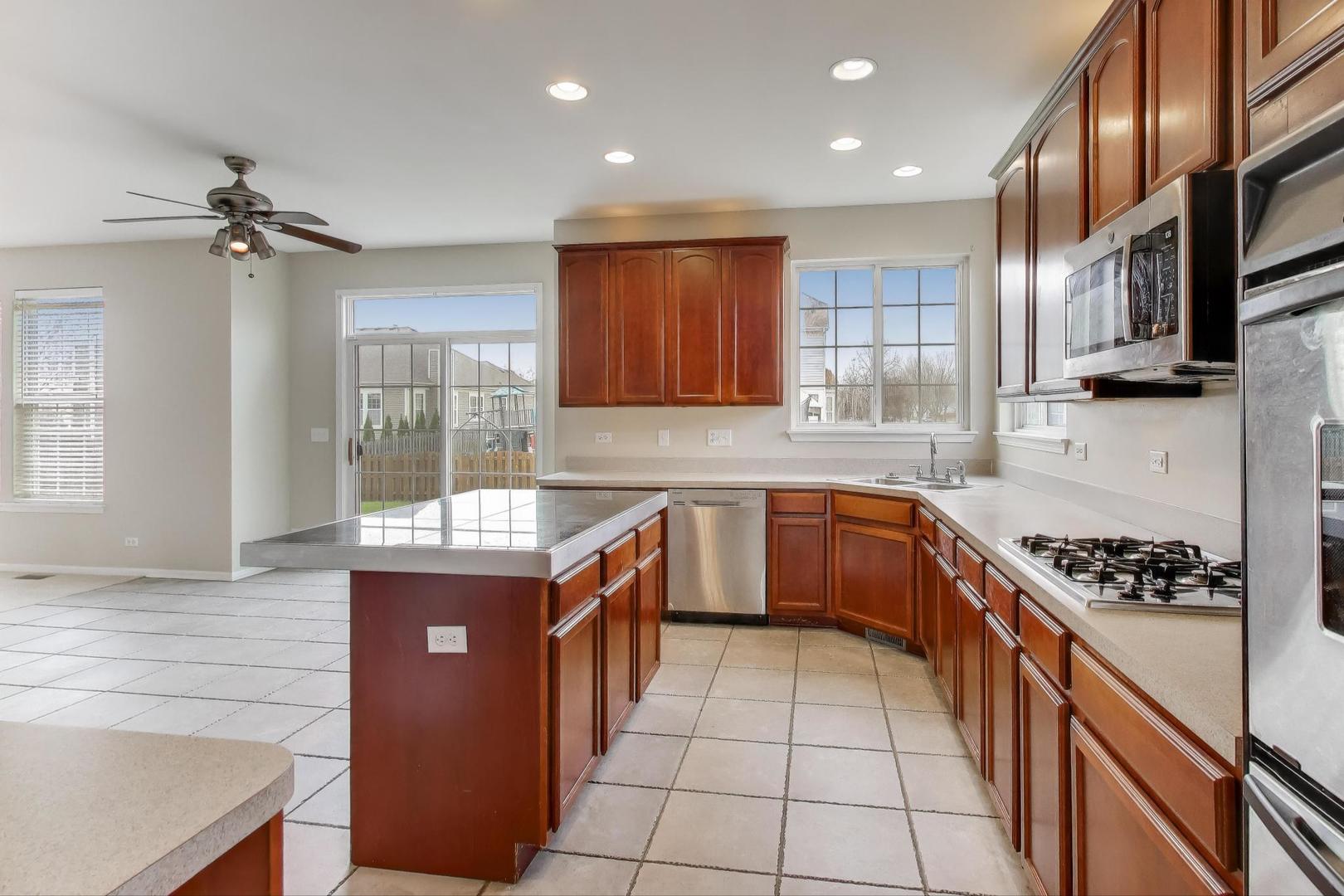 9699 Fairfield Road Huntley, IL 60142 - Photo 15 of 59 a kitchen with stainless steel appliances granite countertop a stove a sink and a microwave