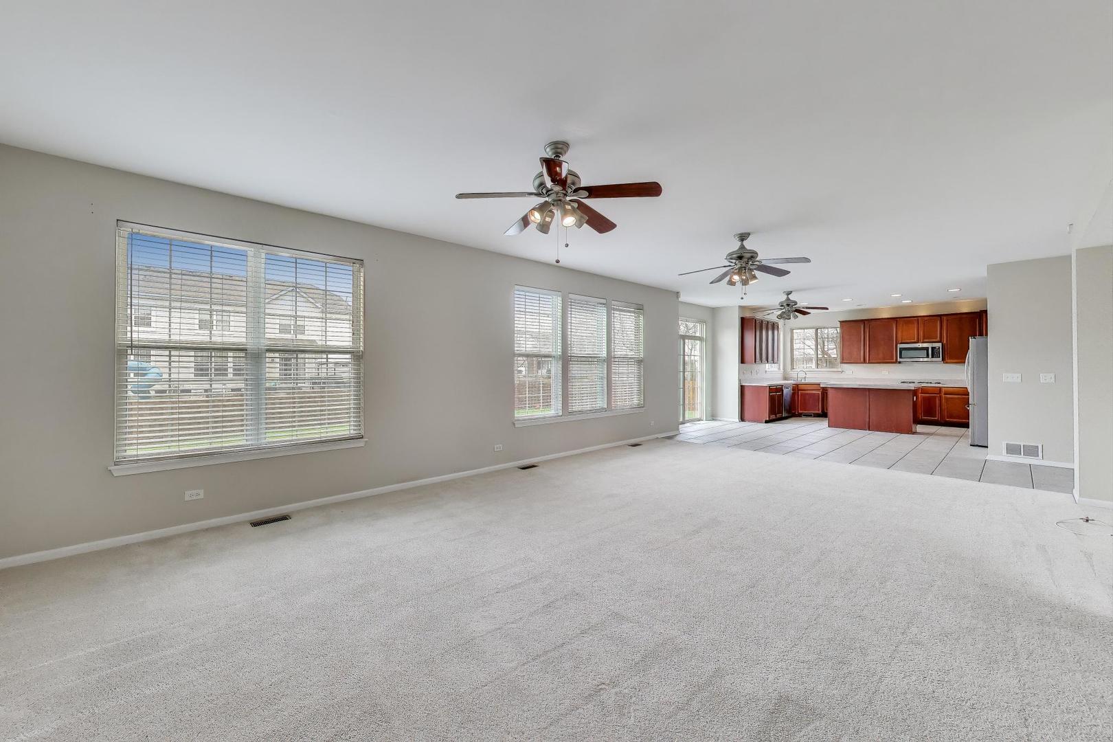 9699 Fairfield Road Huntley, IL 60142 - Photo 19 of 59 an empty room with chandelier fan and windows