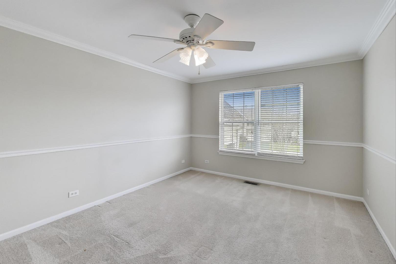 9699 Fairfield Road Huntley, IL 60142 - Photo 37 of 59 an empty room with a chandelier fan and windows