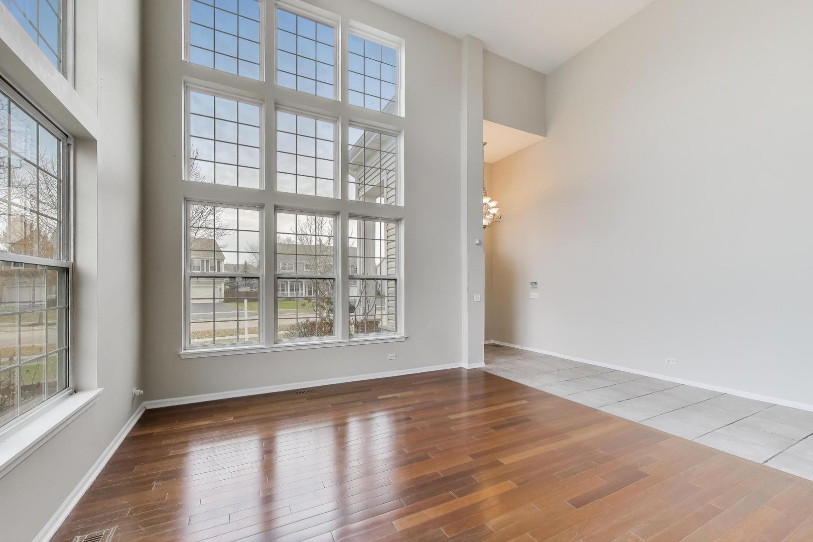 9699 Fairfield Road Huntley, IL 60142 - Photo 7 of 59 an empty room with wooden floor and windows