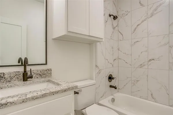 a bathroom with a granite countertop bathtub sink vanity and toilet