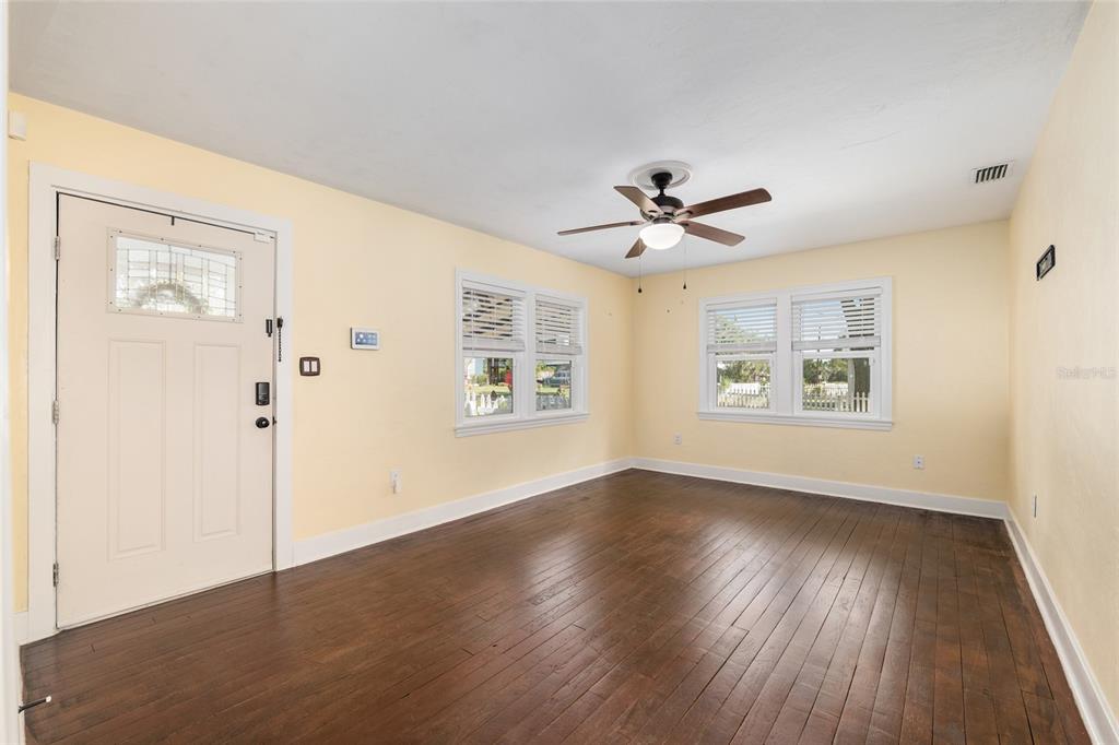 742 Southeast 12th Street Ocala, FL 34471 - Photo 6 of 44 an empty room with wooden floor chandelier fan and windows