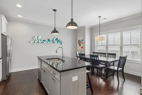 a kitchen with stainless steel appliances granite countertop a sink a stove and chairs