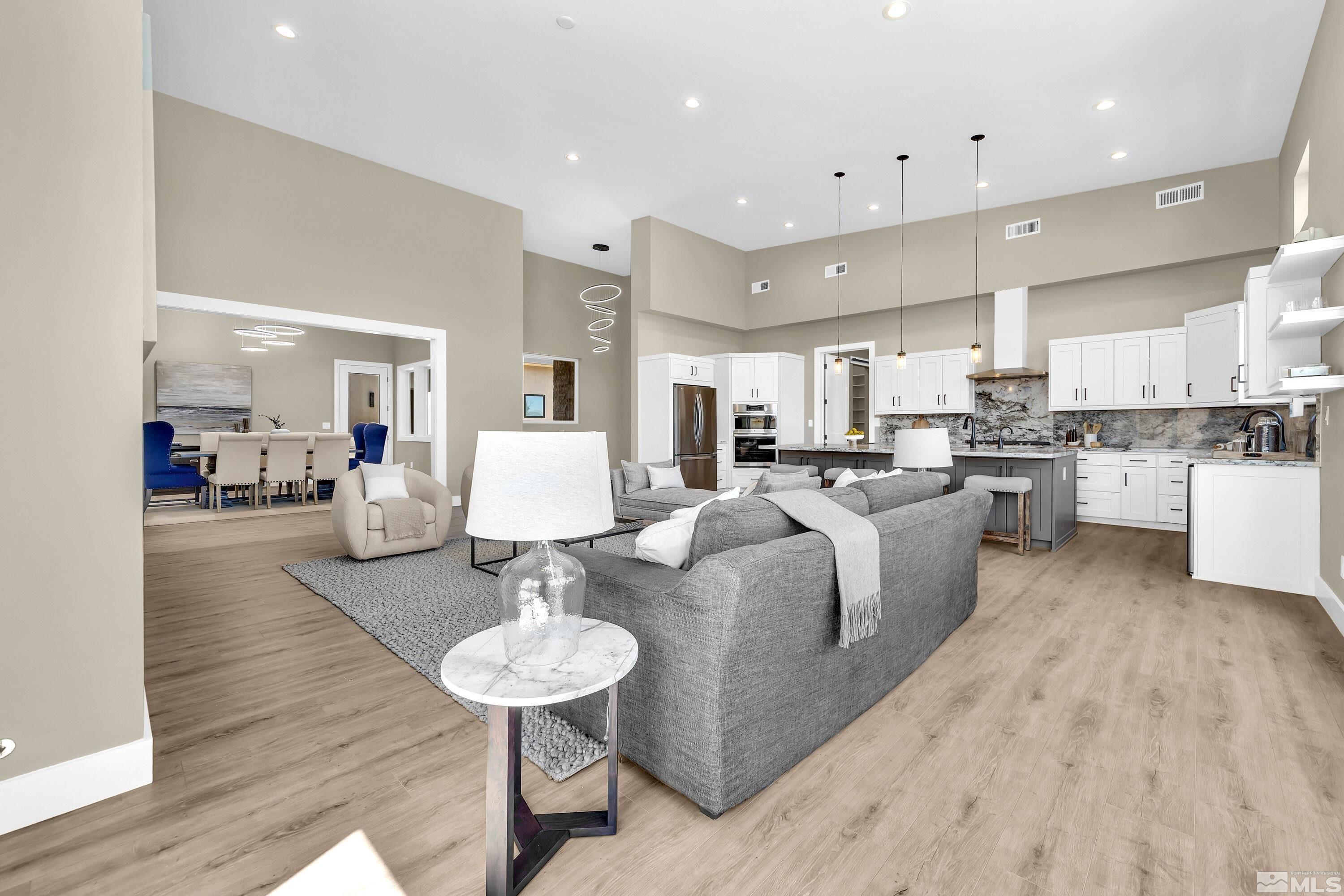 724 Canter Way Reno, NV 89511 - Photo 16 of 40 a large kitchen with kitchen island a island a sink a stove and a dining table with wooden floor