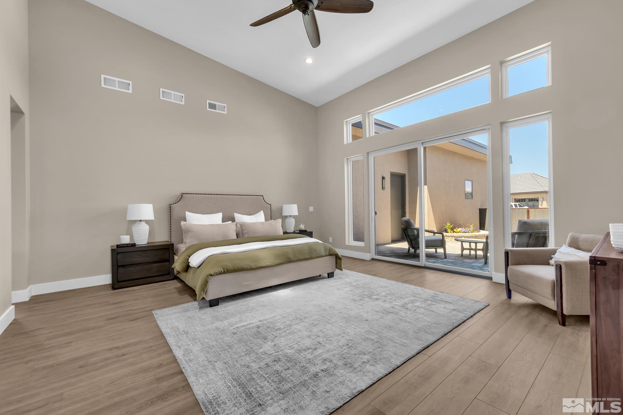 724 Canter Way Reno, NV 89511 - Photo 23 of 40 a spacious bedroom with a bed a couch and a chandelier fan