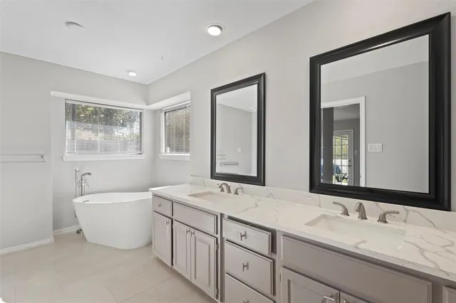 a bathroom with double vanity sinks double vanity tub and a mirror