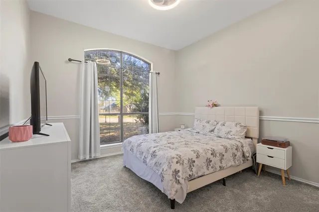 a bedroom with a bed and a flat tv screen next to a window