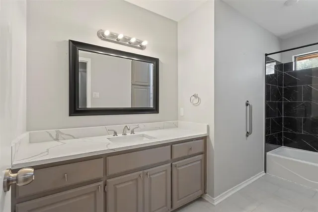 a bathroom with a double vanity sink a large mirror and a bathtub