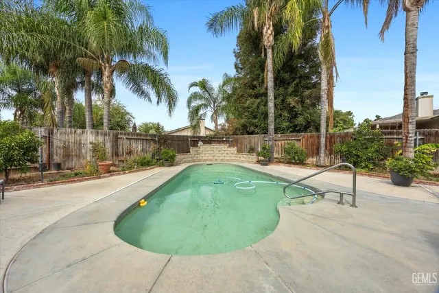 a view of a swimming pool with a patio and palm trees