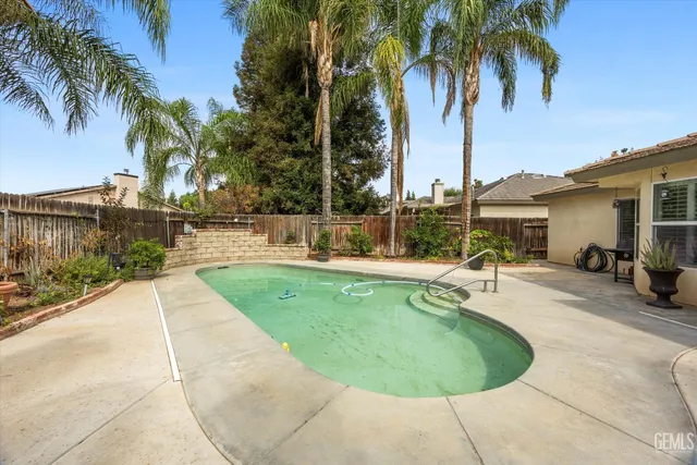 a view of a swimming pool with a patio and a yard
