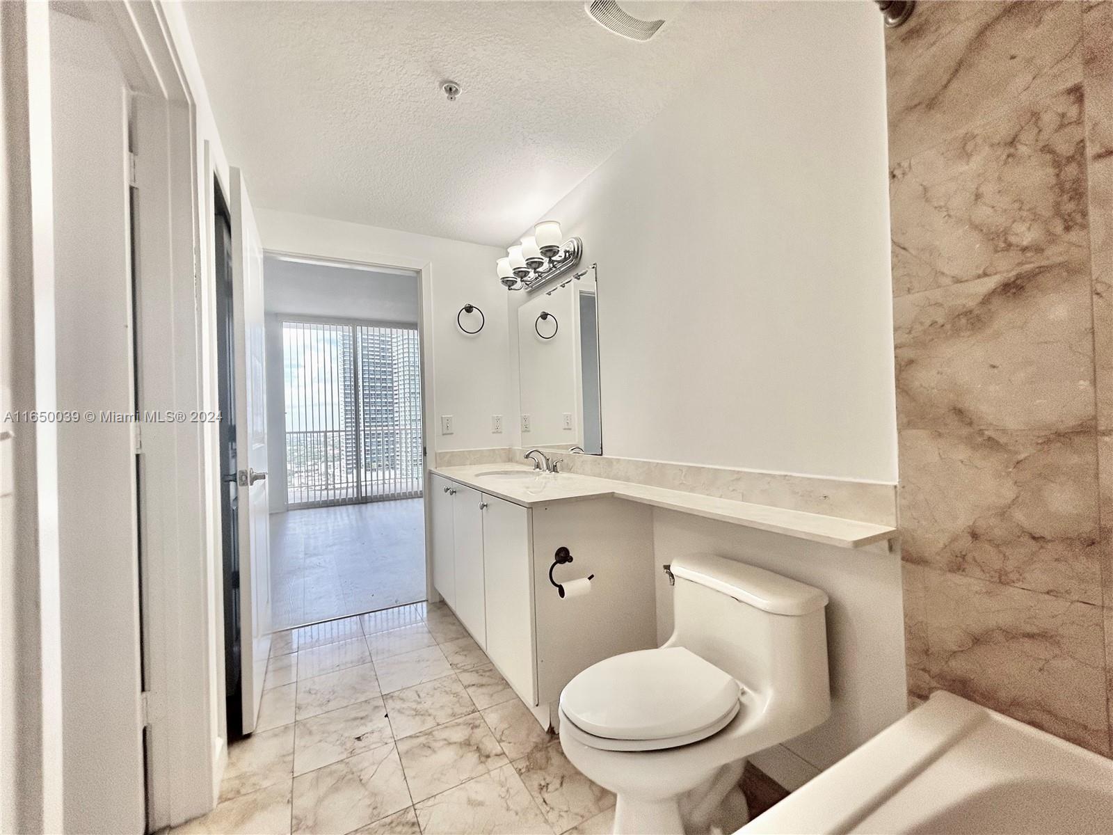 170 Southeast 14th Street, Unit 2906 Miami, FL 33131 - Photo 12 of 31 a bathroom with a granite countertop toilet a sink and a mirror
