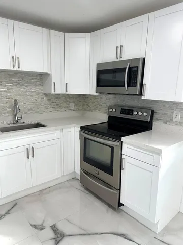 a kitchen with white cabinets and stainless steel appliances