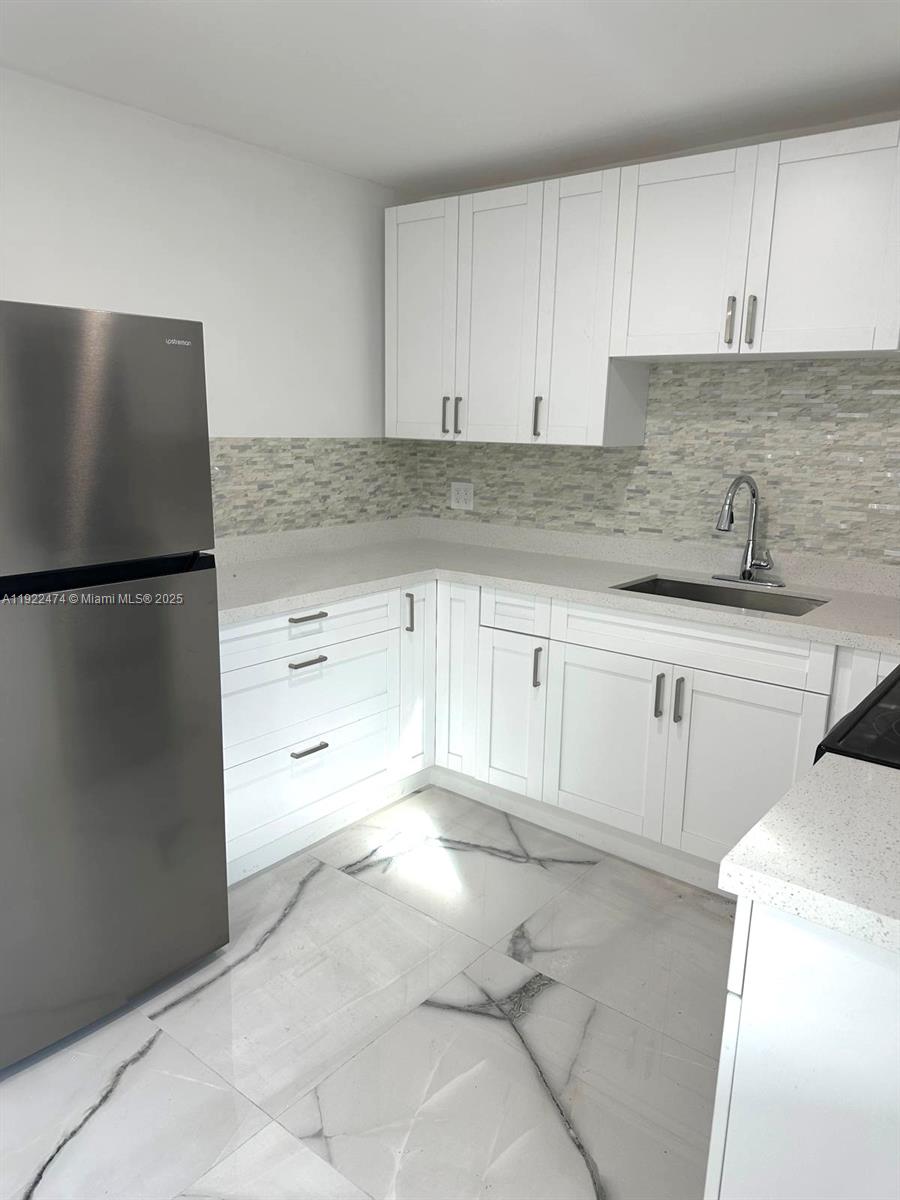 26205 Southwest 133rd Court, Unit 2 Homestead, FL 33032 - Photo 2 of 17 a kitchen with granite countertop white cabinets and refrigerator
