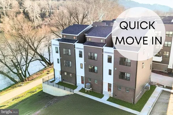 a front view of a building with retail shops and large trees