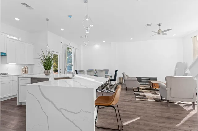 a room with kitchen island white cabinets and stainless steel appliances