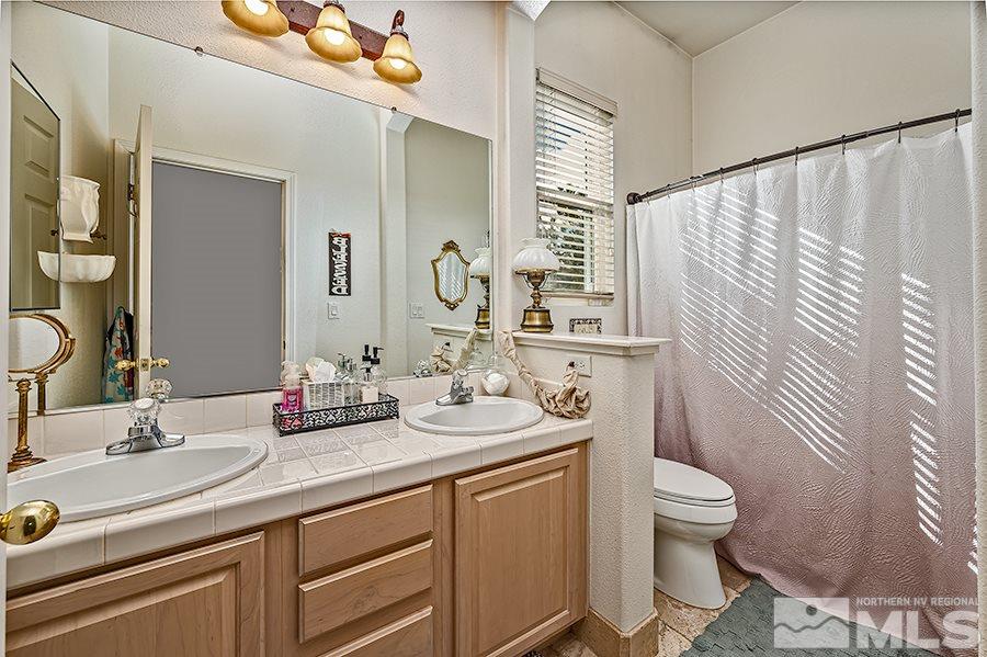 10155 Buckeye Court Reno, NV 89521 - Photo 14 of 17 a bathroom with a granite countertop sink mirror vanity and toilet