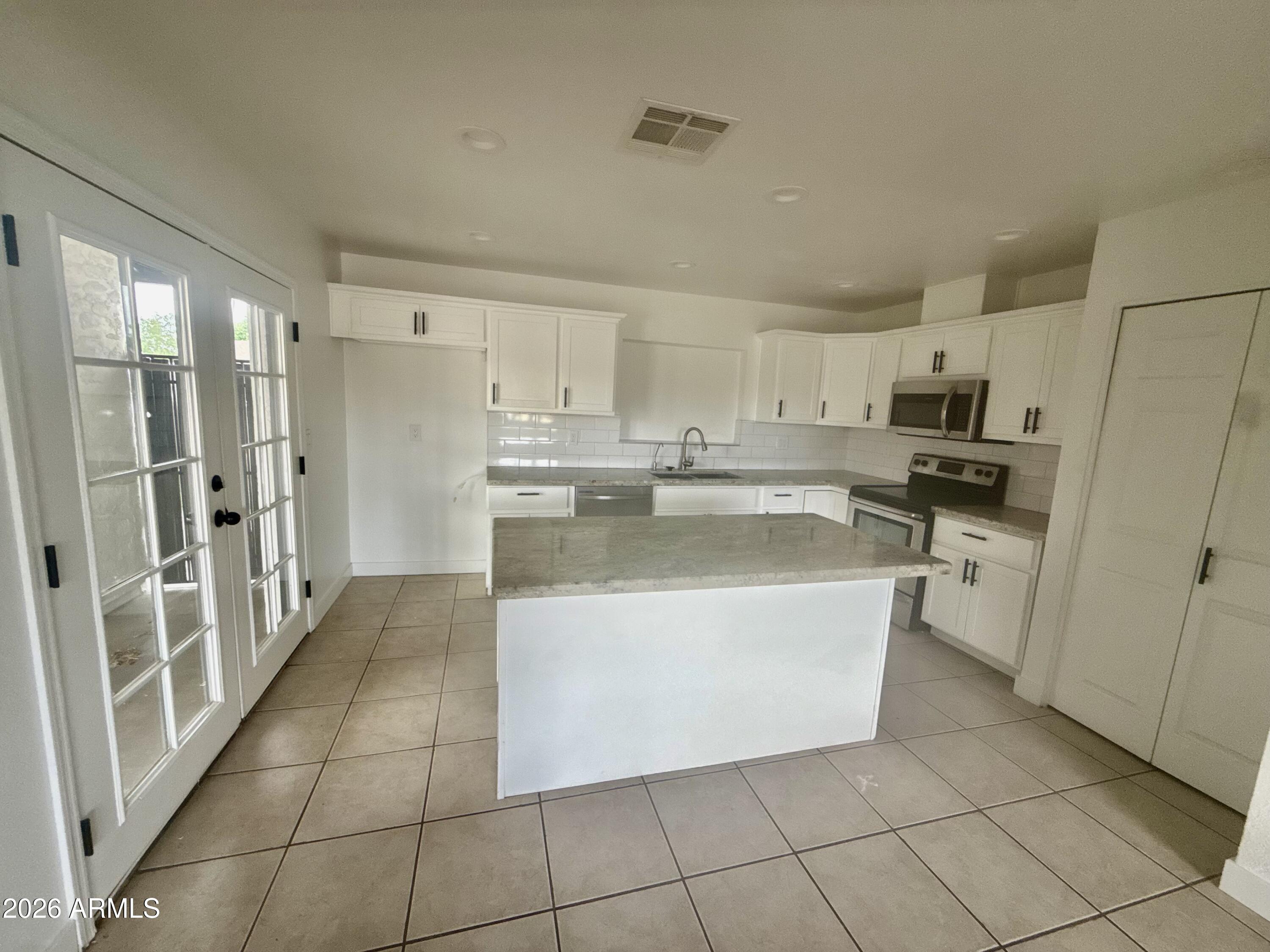 6963 West Rancho Drive Glendale, AZ 85303 - Photo 3 of 14 a kitchen with stainless steel appliances a refrigerator sink and cabinets