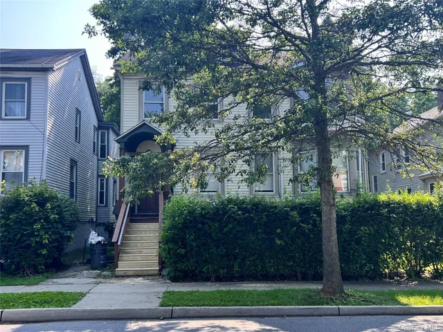 a front view of a house with plants and trees