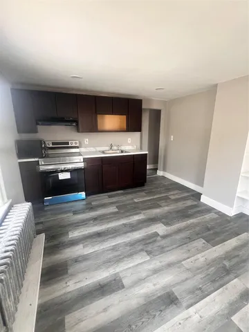 a view of kitchen with kitchen island stainless steel appliances wooden floor and living room