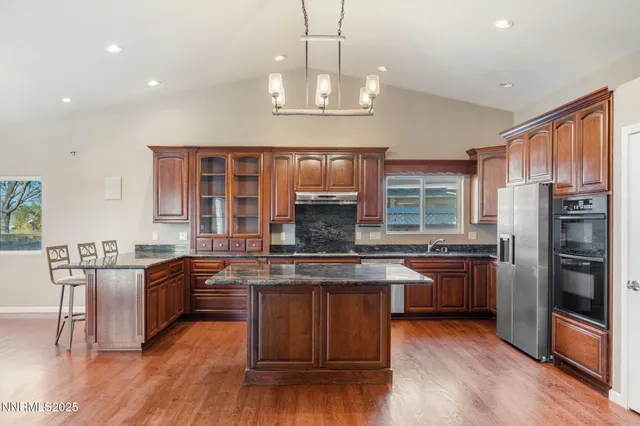 a kitchen with stainless steel appliances granite countertop wooden floors and view living room
