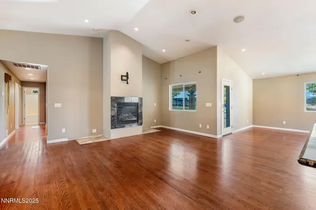 a view of an empty room with wooden floor and a fireplace