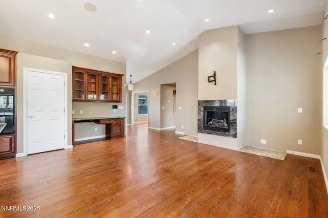 an empty room with wooden floor fireplace and cabinet