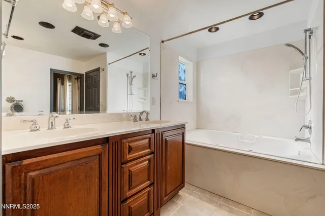 a bathroom with a granite countertop sink a large mirror and a bathtub
