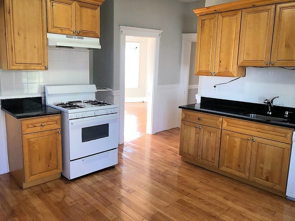 19 Arden Street, Unit 2 Boston, MA 02134 - Photo 8 of 8 a kitchen with granite countertop wooden cabinets and a stove top oven