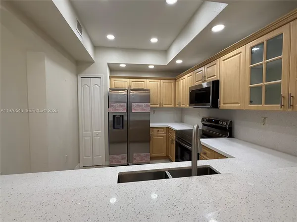 a kitchen with stainless steel appliances granite countertop a refrigerator a stove a sink and a microwave