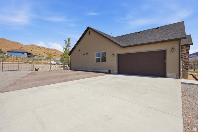 1588 West Rim Rock Drive Stockton, UT 84071 - Photo 50 of 61 Stucco exterior with a dark brown garage door and a gravel driveway